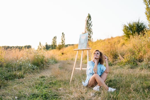 Pretty talented female painter painting on easel, making colorful sketches, creating marine landscape. Beautiful female artist painting with watercolor paints. Creativity and imagination concept photo