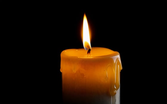 yellow burning candle with dripping wax photo
