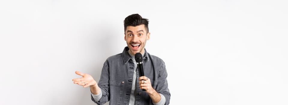 Handsome smiling performer talking in mic, gesturing and performing, making speech with microphone, standing against white background photo
