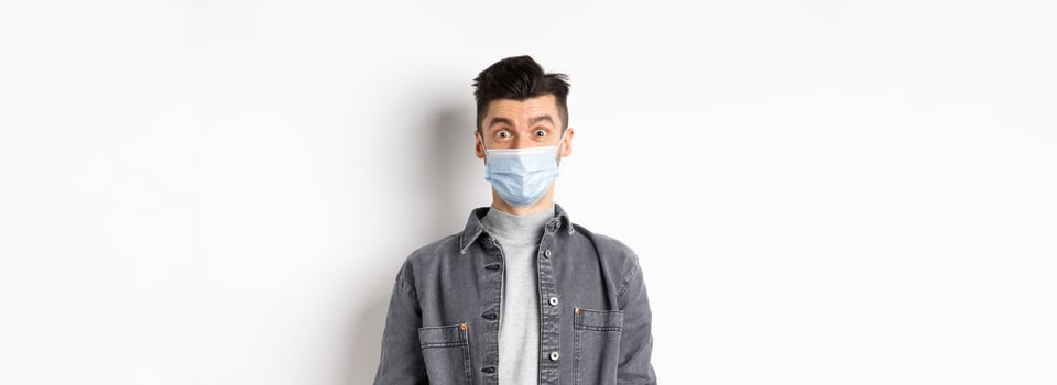 Health, covid and pandemic concept. Happy young man use medical mask from catching coronavirus, social distancing during quarantine, white background photo