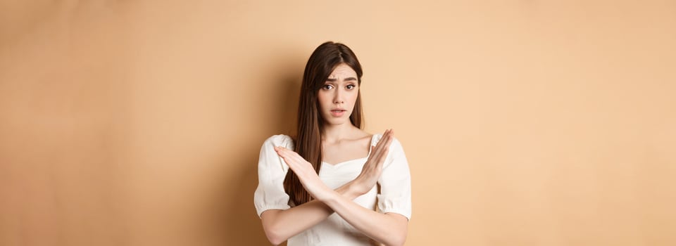Girl says no. Skeptical young woman disagree or prohibit action, showing cross stop gesture, make nope sign, disapprove bad idea, standing on beige background photo