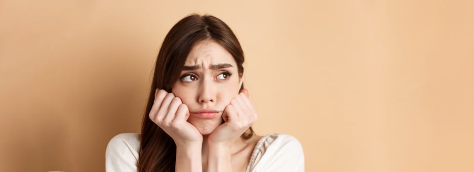 Close up of sad and gloomy girl looking aside, sulking and frowning upset, standing miserable on beige background photo
