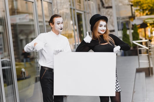 Your text here. Actors mimes holding empty white letter. Colorful portrait with gray background. April fools day photo