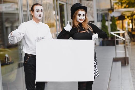 Your text here. Actors mimes holding empty white letter. Colorful portrait with gray background. April fools day photo