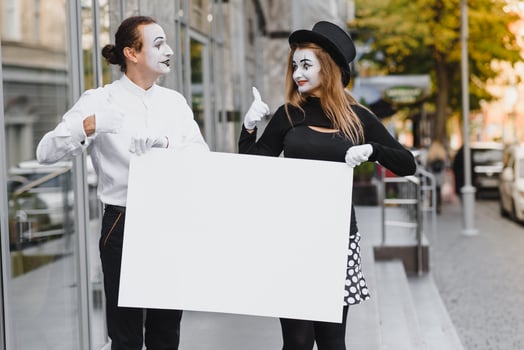 Your text here. Actors mimes holding empty white letter. Colorful portrait with gray background. April fools day photo