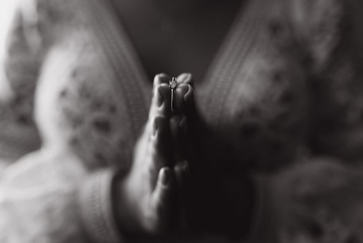 bride holds wedding ring on her hand against the background of a white lace wedding dress. body parts, hold hands. photo