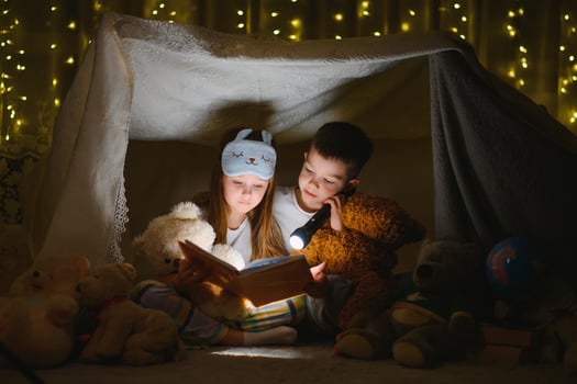reading and family games in children's tent. boy and girl with book and flashlight before going to bed photo