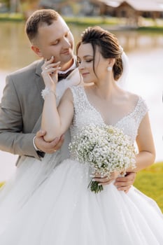 A bride and groom are posing for a picture. The bride is holding a bouquet of white flowers photo