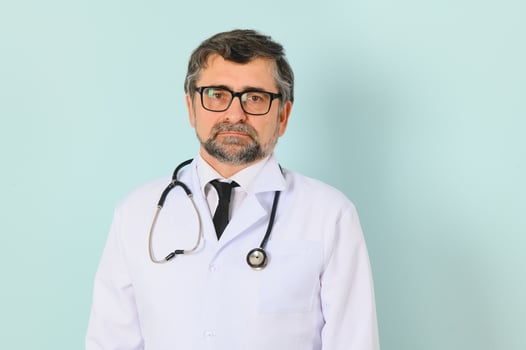 Senior doctor man wearing stethoscope and medical coat oveer blue background photo