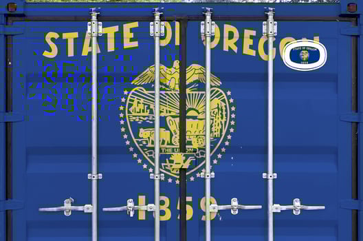 Oregon US state flag depicted on metal doors of shipping cargo container outdoors in docks area photo