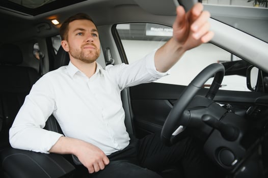 Handsome businessman driving car before buying photo