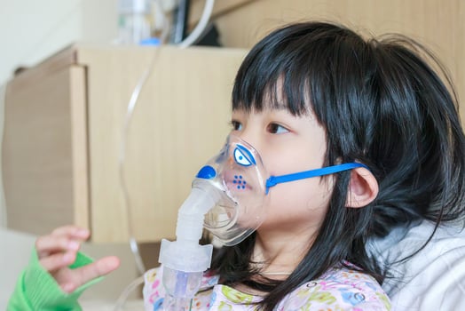 Sick little asian girl inhalation with nebulizer for respiratory treatment photo