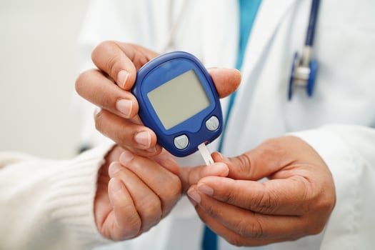 Asian doctor using digital glucose meter for check sample blood sugar level to treatment diabetes. photo