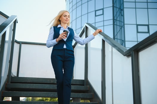 Beautiful Woman Going To Work With Coffee Walking Near Office Building. Portrait Of Successful Business Woman Holding Cup Of Hot Drink. photo