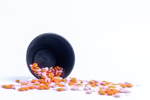 Multicolor pills spilling out of spilled from black plastic box on white background. closeup photo