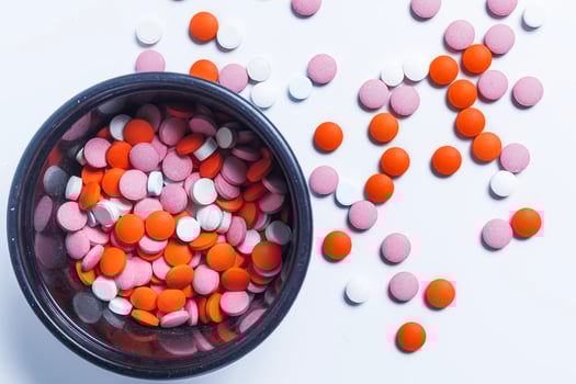 Colorful pills in a round plastic container on a white background and pills scattered from it. photo