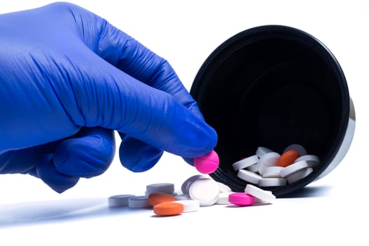 Blue gloved doctor's hand holding pink color pill photo