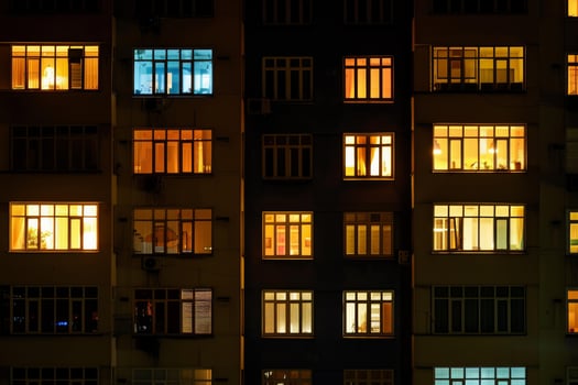 Facade of apartment building at night showing life inside through lit windows photo