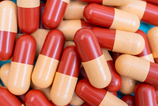 Medicine pills or capsules on blue background with copy space. Medicinal prescription for drug treatment. Pharmaceutical drug, medicine in container for health. Sale of antibiotic in pharmacy. photo