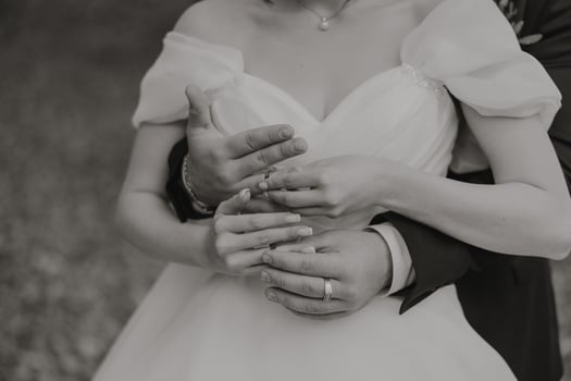 A bride and groom are embracing each other, with the bride wearing a white dress photo