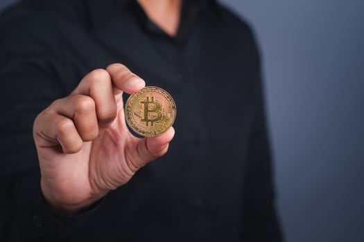 Investor guy showing a bitcoin golden coin with a dark gray background. Close-up photo. Space for text. Virtual cryptocurrency and future money concept photo