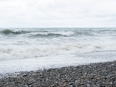Storm waves on a stone beach in cloudy weather photo