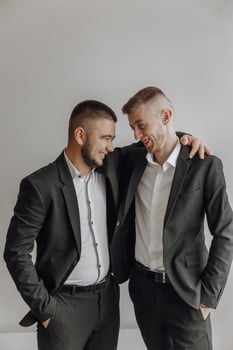 Two men in suits are smiling and hugging each other. Scene is happy and friendly photo