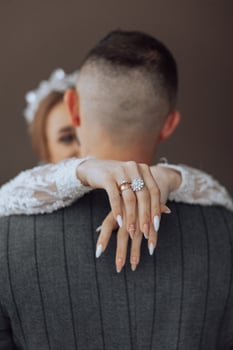 A man and woman are embracing each other, with the woman holding the man's hand and the man holding the woman's ring photo