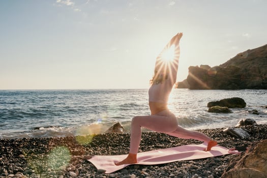 Woman sea yoga. Happy woman with black hair doing Pilates with the ring on the yoga mat near the sea on the pebble beach. Female fitness yoga concept. Healthy lifestyle, harmony and meditation. photo