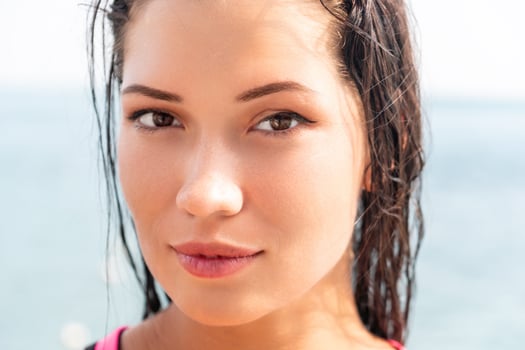 Woman sea sup. Close up portrait of beautiful young caucasian woman with black hair and freckles looking at camera and smiling. Cute woman portrait in a pink bikini posing on sup board in the sea. photo