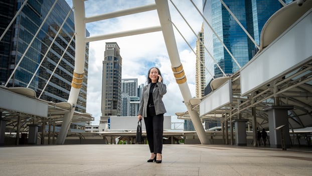 A professional mature Asian businesswoman is talking on the phone while walking in the urban city. photo