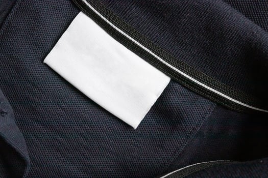 Blank white laundry care clothes label on black shirt fabric texture background photo