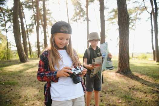 boy and girl go hiking with backpacks on forest road bright sunny day photo