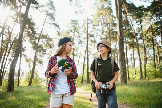Happy excited school children with backpacks in casual clothes enjoying walk in forest on sunny autumn day, two active kids boy and girl running and playing together during camping trip in nature. photo