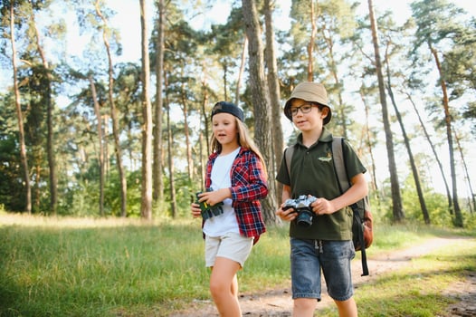 boy and girl go hiking with backpacks on forest road bright sunny day photo