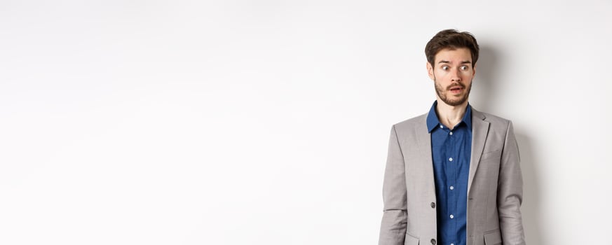 Shocked male entrepreneur in suit looking aside at logo with startled face, standing on white background photo