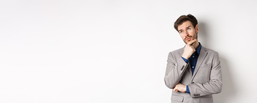 Thoughtful businessman in grey suit look at upper left corner logo, thinking or making choice, pondering plan, standing against white background photo