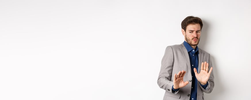 Stay away. Reluctant businessman step back with concerned disgusted face, raising hands to block bad offer, rejecting something awful, tilting from disgust, white background photo
