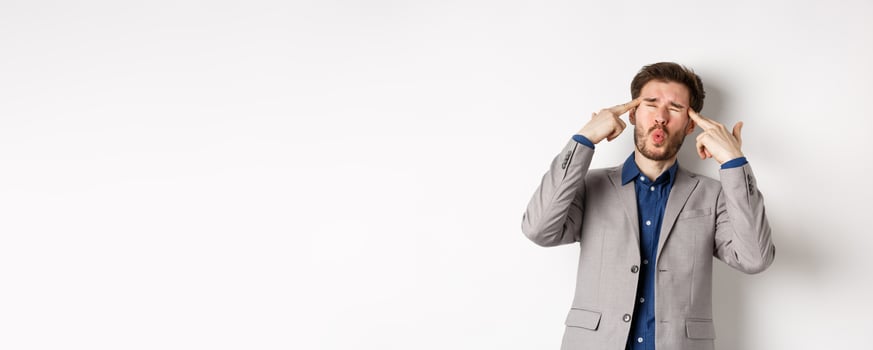 Distressed and tensed businessman pointing at head and complaining, feeling annoyed with situation blowing his mind, standing bothered on white background photo