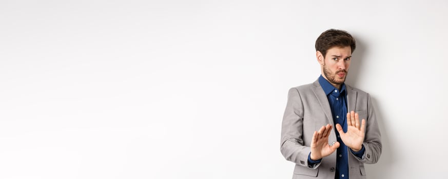 Stay away. Reluctant businessman step back with concerned disgusted face, raising hands to block bad offer, rejecting something awful, telling no and decline proposal, white background photo