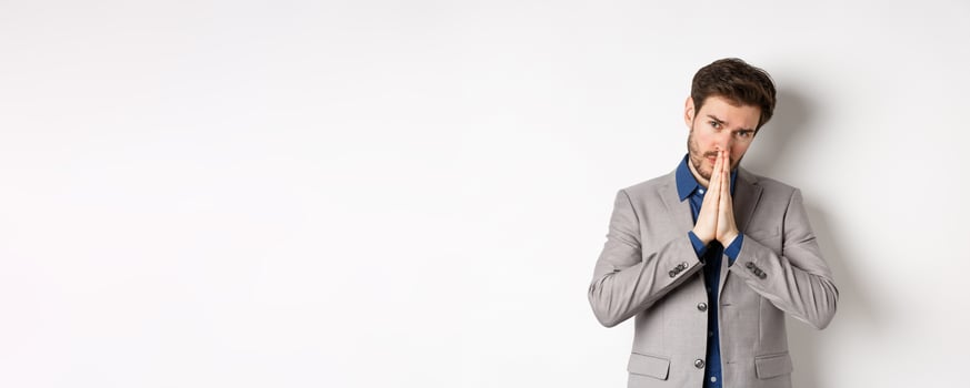 Please help. Pleading man in suit asking for favour, begging you, standing on white background photo