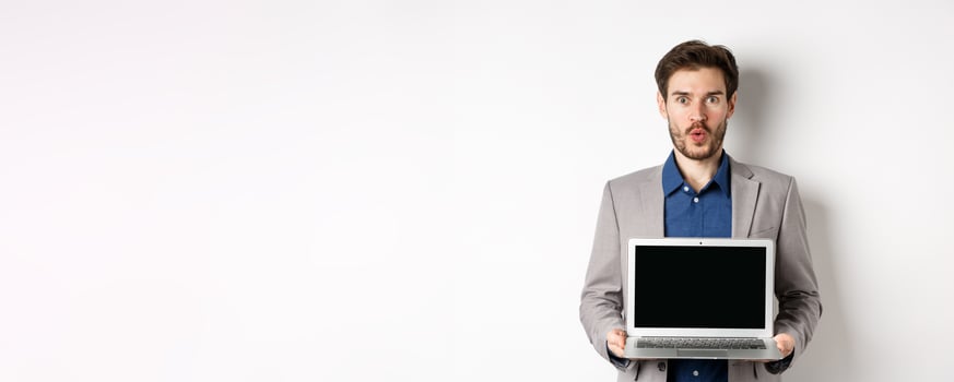 Handsome caucasian businessman in suit showing empty laptop screen, demonstrate promo, standing on white background photo