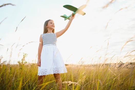 Happy kid with toy plane is playing at sunset photo