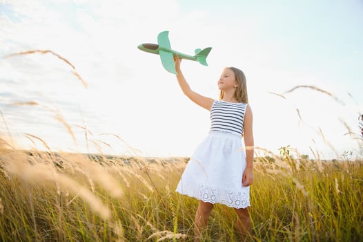 Happy girl runs with a toy airplane on a field in the sunset light. children play toy airplane. teenager dreams of flying and becoming a pilot. girl wants to become a pilot and astronaut. Slow motion. photo