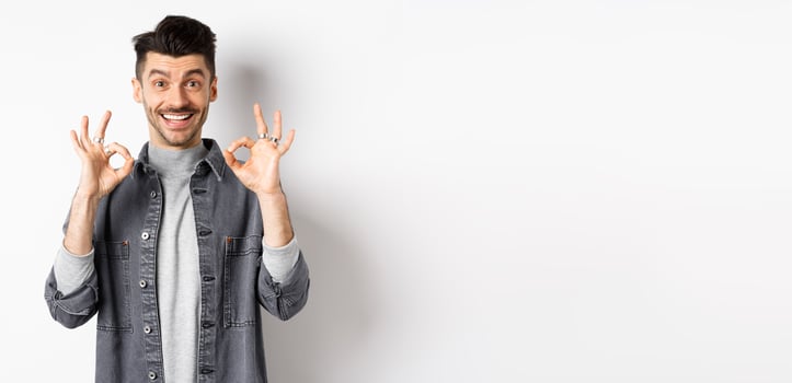 Happy guy say yes, smiling and showing okay signs, like good product, nod in approval and make satisfied face, praise excellent work, standing on white background photo