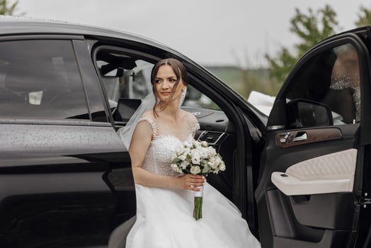 A bride is sitting in the back of a car with a bouquet of flowers photo