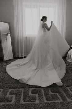 A woman in a wedding dress is standing in front of a mirror photo