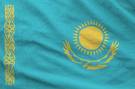 Kazakhstan flag depicted on folded wavy fabric of old cloth photo