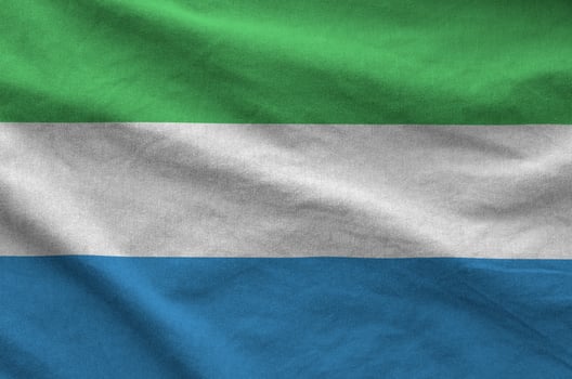 Sierra Leone flag depicted on folded wavy fabric of old cloth photo