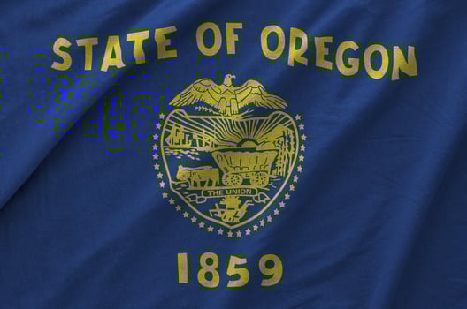 Oregon US state flag depicted on folded wavy fabric of old cloth photo